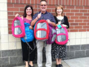 From left, principals Laura Bolt, Rex Larson and Mary Lou Woody display backpacks their schools received, filled with supplies, for children in need.