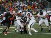 Camas High School seniors Vince Huber (21) and Nick Gadbaw (22) smother the Canby quarterback Friday, at Doc Harris Stadium.