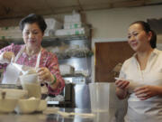 Thanh Tran, left, matriarch of the family that founded the popular Four Sisters restaurant in Falls Church, Va., demonstrates how to make Song Que's Bananas With Tapioca Pearls, aided by daughter Lieu Lai.