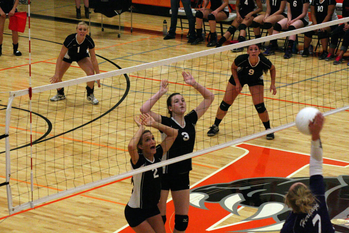 Washougal volleyball players Paige Bentley (2) and Carly Morris (3) reach up to protect the net. The Panthers played on their new floor for the first time Sept. 10.