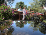 Mark Pollock and Kathy Roby are reflected in a birdbath in their memory garden at their home in Suffield Township, Ohio.