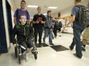 With the help of his friend Zechariah Maniar, 16, Justin Carey uses a wheelchair to make his way through the halls of Battle Ground High School on the first day of school Wednesday.