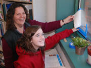 Sandi Christensen, Canyon Creek Middle School principal, and seventh-grader Natalie Garner proudly display the Energy Star decal earned as a result of energy improvements at the school.