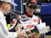 Driver Greg Biffle, right, signs an autograph for a fan as he walks to his garage during practice for Sunday's NASCAR Sprint Cup Series auto race at Chicagoland Speedway in Joliet, Ill., Friday, Sept. 13, 2013. (AP Photo/Nam Y.