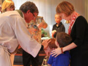 The Rev. Chip Stokes bestows a blessing on Thomas Barken-Stewart, 3, who is with his mother, Jacqueline Barken, and brother, Joshua Barken-Stewart, at a service at St. Paul's Episcopal Church in Delray Beach, Fla.