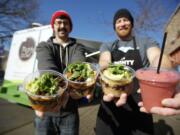 Steve Valenta, left, and Kevin DeGraw show off the Kiggins Bowl, from left, the Mighty Bowl, the Peanut Bowl and the Carter Park smoothie outside their mobile food truck.