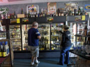 By The Bottle owner Arlene Nunez, right, helps a customer pick out beer in August.