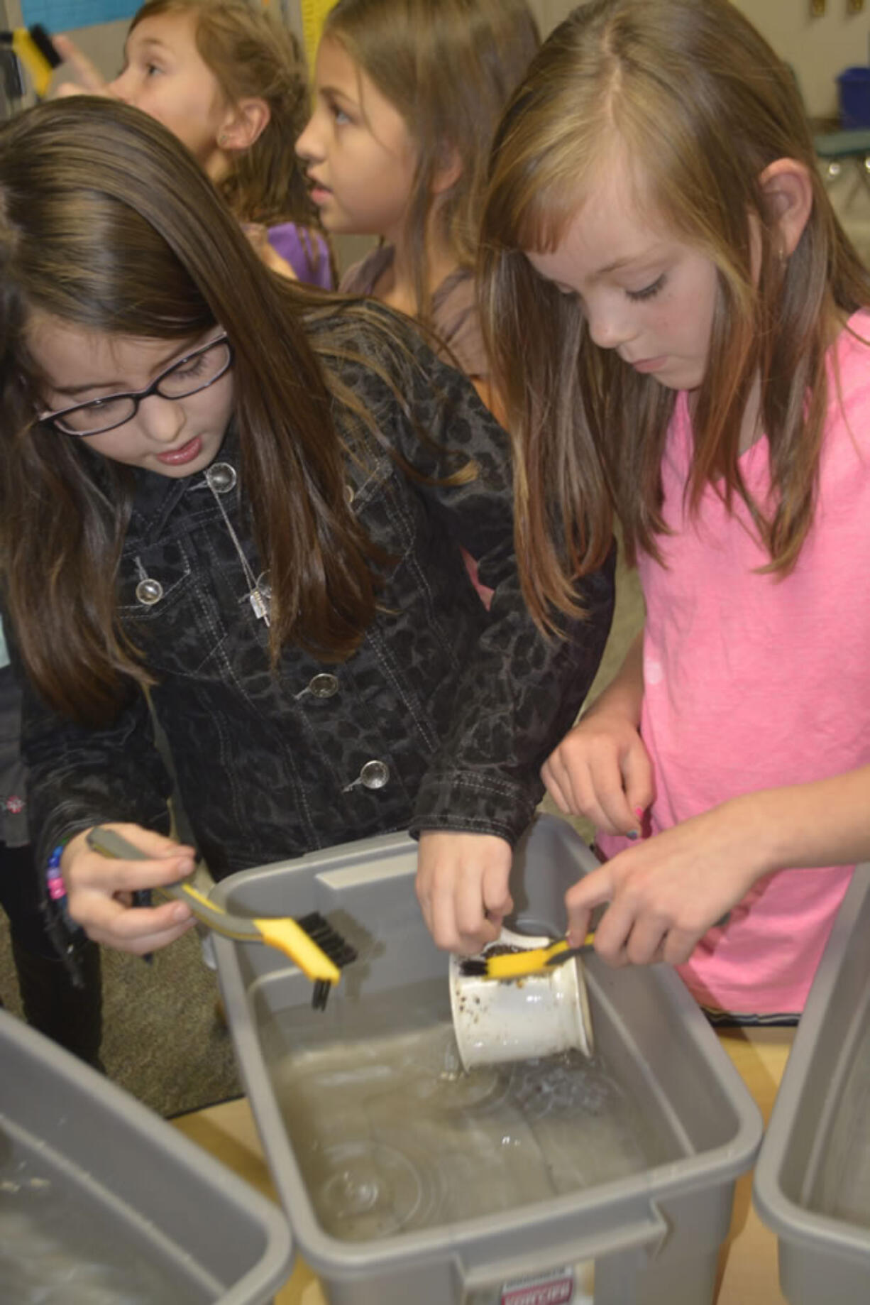 Cape Horn-Skye Elementary third-graders Megan West and Kylie Bowen wash a turn-of-the-century cup as they learn more about the role of archeologists.