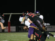 Camas High School seniors Matt Danis (56) and Jorden Payne (3) crumple the Heritage receiver Friday, at Doc Harris Stadium.