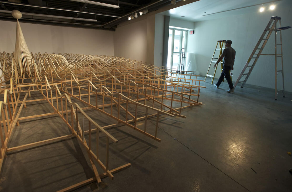 Portland artist Mike Rathbun, right, walks toward the Archer Gallery door Monday while setting up his installation -- &quot;Attend&quot; -- at Clark College.