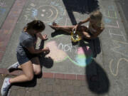 Junior Joy Team members Abigail Brooks, 12, left, and Sierra Watters, 12, were among about three dozen children who decorated the sidewalks on Main Street on Tuesday with colorful, positive pictures and messages during the third annual Chalk the Walks.