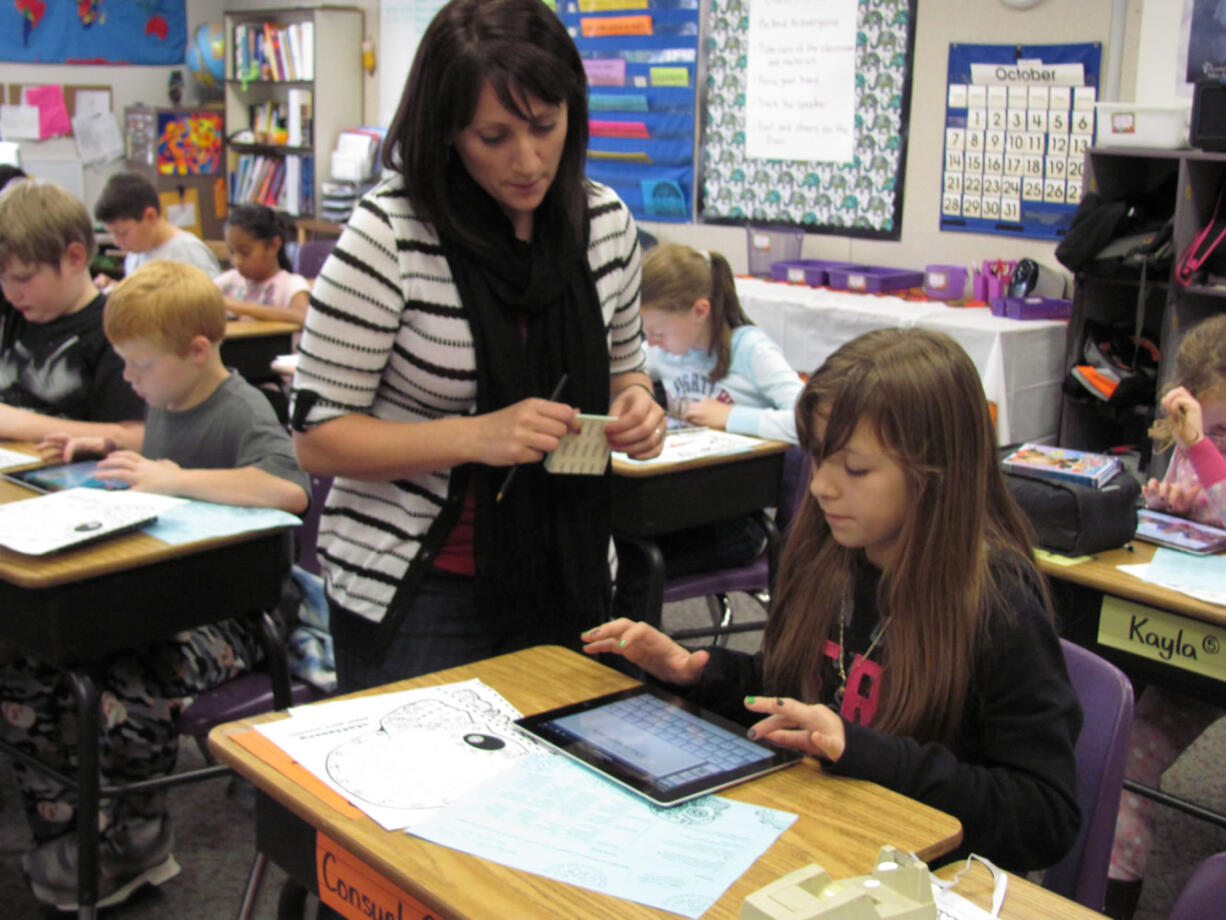 Hathaway Elementary School fifth-grade teacher Erin Hayes assists Consuelo Martinez with a research question. The students in Hayes' class are part of a district-wide iPad pilot group.