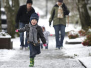 Nolan Bain, 3, frolics in the snow on a morning walk March 22 with his family -- Brian Bain, left, Aurora, 16 months, and Kirby Bain -- in the Lincoln neighborhood of Vancouver.