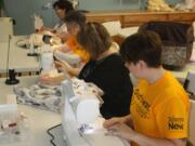 North Image: Maggie Antonelli, from foreground to back, Kari Pinc, Nadine Scott and Michelle Steele sew sheets for the WHO program.