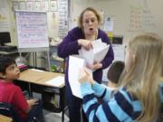 Eileen O'Connor, a fifth-grade teacher at Maple Grove K-8 school, distributes papers to her students the day before spring break. On Feb. 12, Battle Ground was the only school district of 41 in the state that saw its maintenance and operation levy fail.