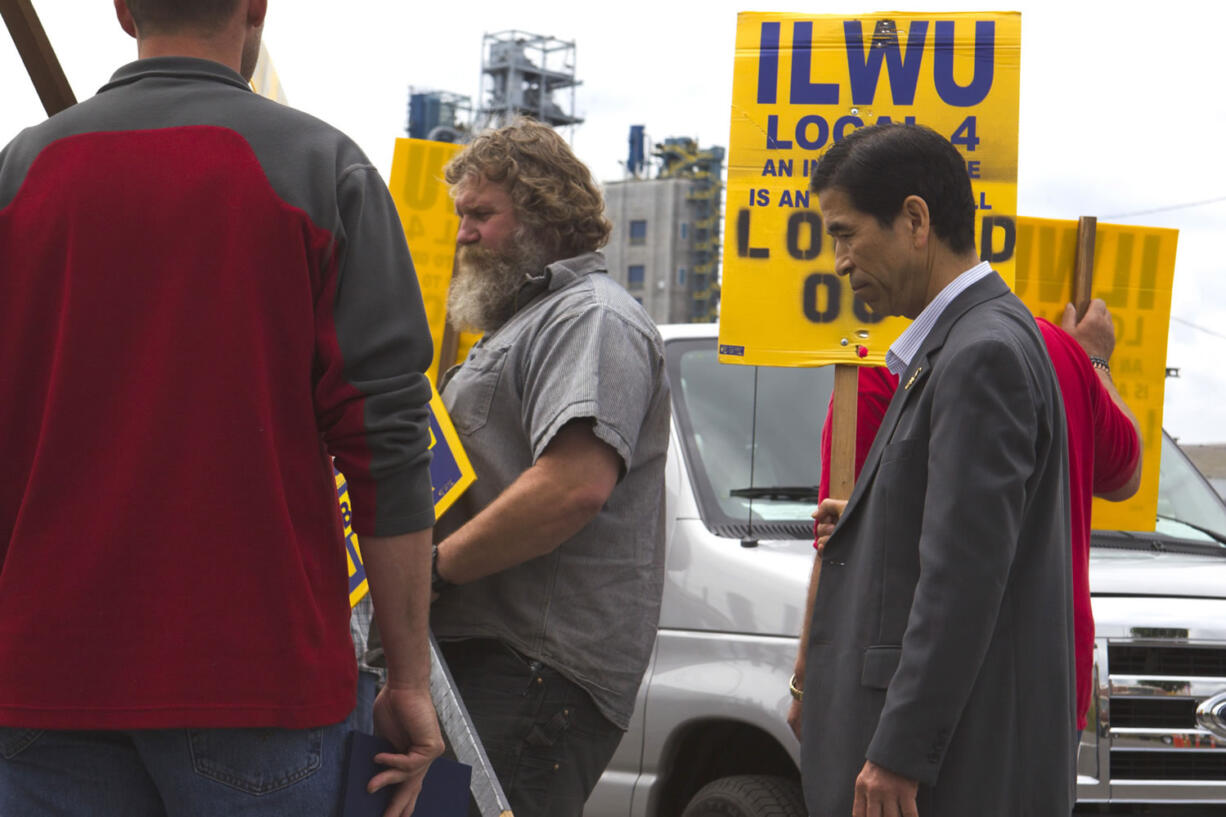 Fusao Ohori, right, a Japanese union leader visiting from Tokyo, joined union dockworkers Friday outside the United Grain Corp.