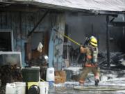 A firefighter pulls metal siding from the shop at the John and Delores Matson residence in Hockinson on Wednesday morning.