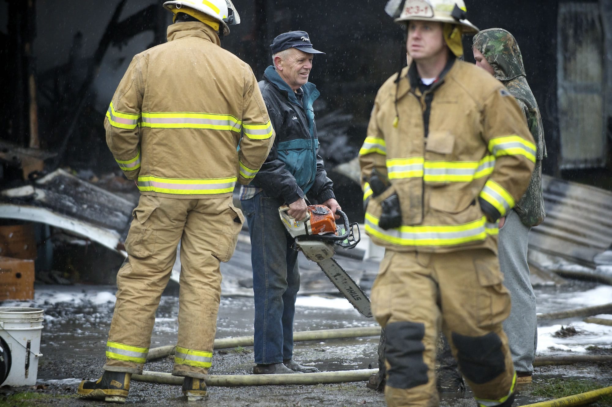 John Matson, center, recovers a chain saw from his ruined shop.