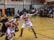 Washougal's Austin Tran rolls by Camas defenders Trent Johnson and Drew Clarkson on a pick set by Aaron Deister.