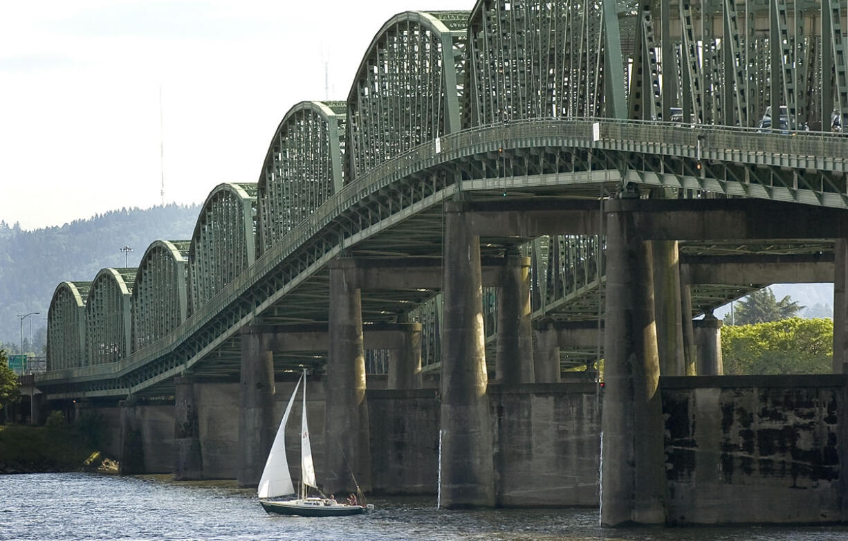A sailboat passes under the Interstate 5 Bridge.