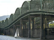 A sailboat passes under the Interstate 5 Bridge.