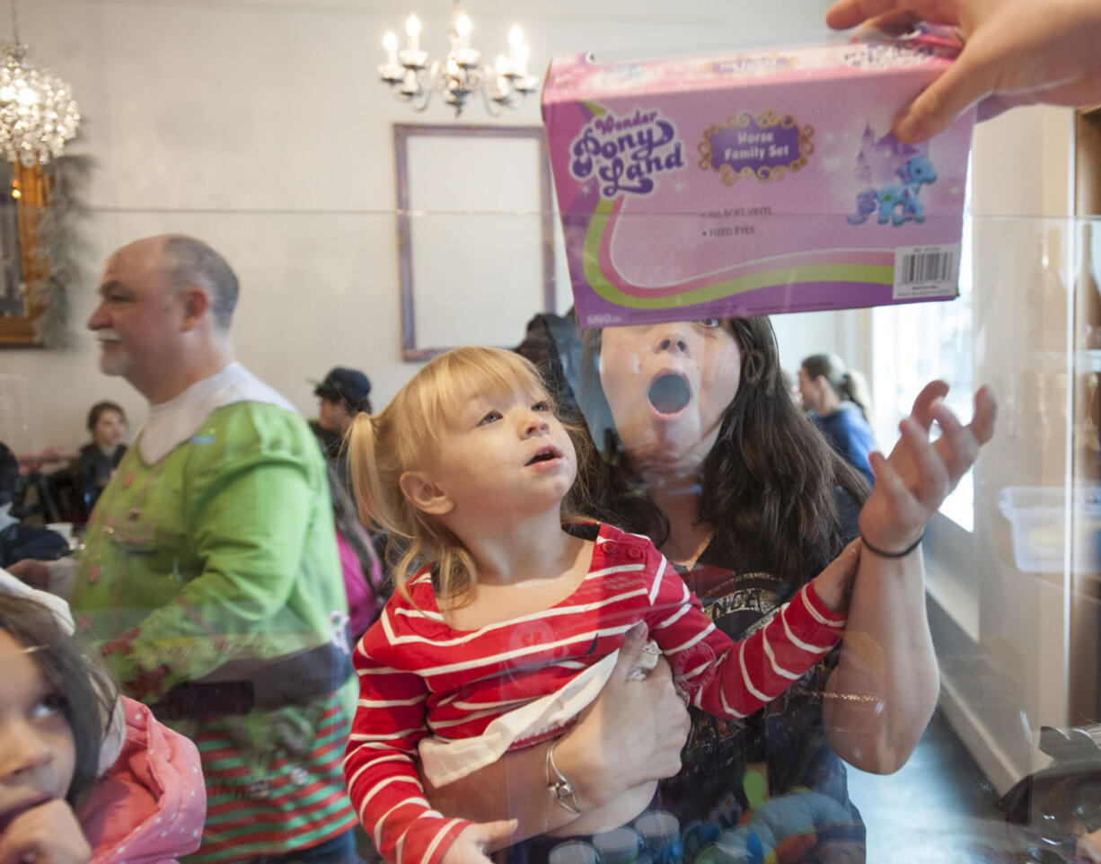 Bridget Klimas reacts as her daughter Harley gets a Christmas present following a free meal at Bleu Door Bakery in Vancouver on Friday. The uptown restaurant served Christmas dinner to the needy and distributed toys and presents to children, with hopes of continuing the holiday tradition for years to come.