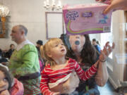 Bridget Klimas reacts as her daughter Harley gets a Christmas present following a free meal at Bleu Door Bakery in Vancouver on Friday. The uptown restaurant served Christmas dinner to the needy and distributed toys and presents to children, with hopes of continuing the holiday tradition for years to come.