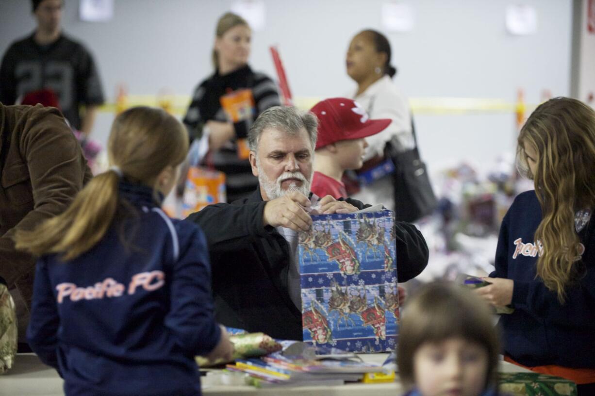 Brian Stansberry wraps Christmas presents as part of Santa's Posse. He and his wife learned of the program from a granddaughter and decided to go volulunteer.