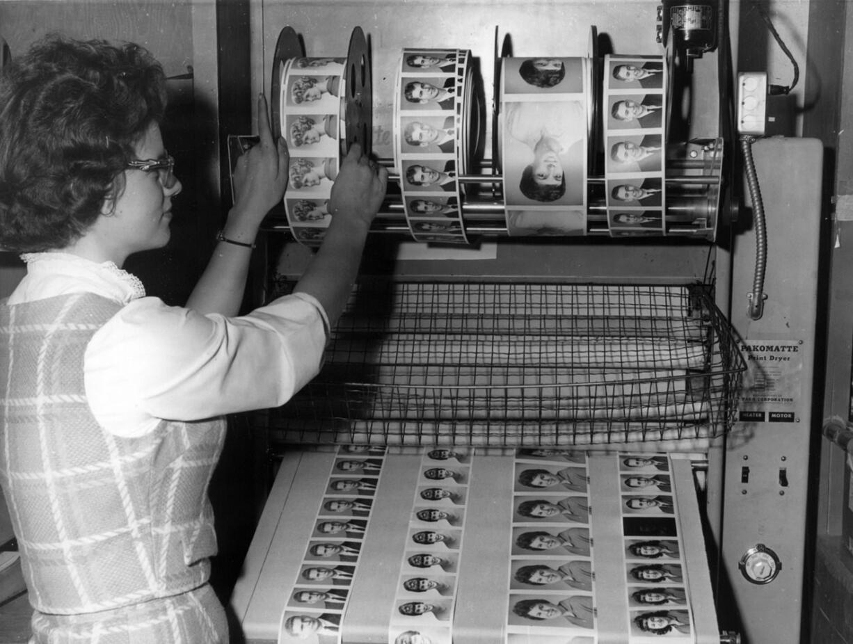 A Bruno Portrait Studio employee feeds rolls of wet film through a print-drying machine at the downtown Vancouver studio in 1961.