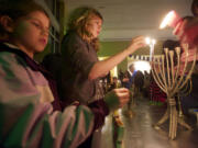 Sisters Bailey VanRoy-Amundson, left, and Anna VanRoy-Amundson, light menorahs at the Congregation Kol Ami Hanukkah party.