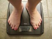 Laina Harris steps on the scale in her Camas home Wednesday. Harris weighs herself every day to monitor her weight-loss progress.