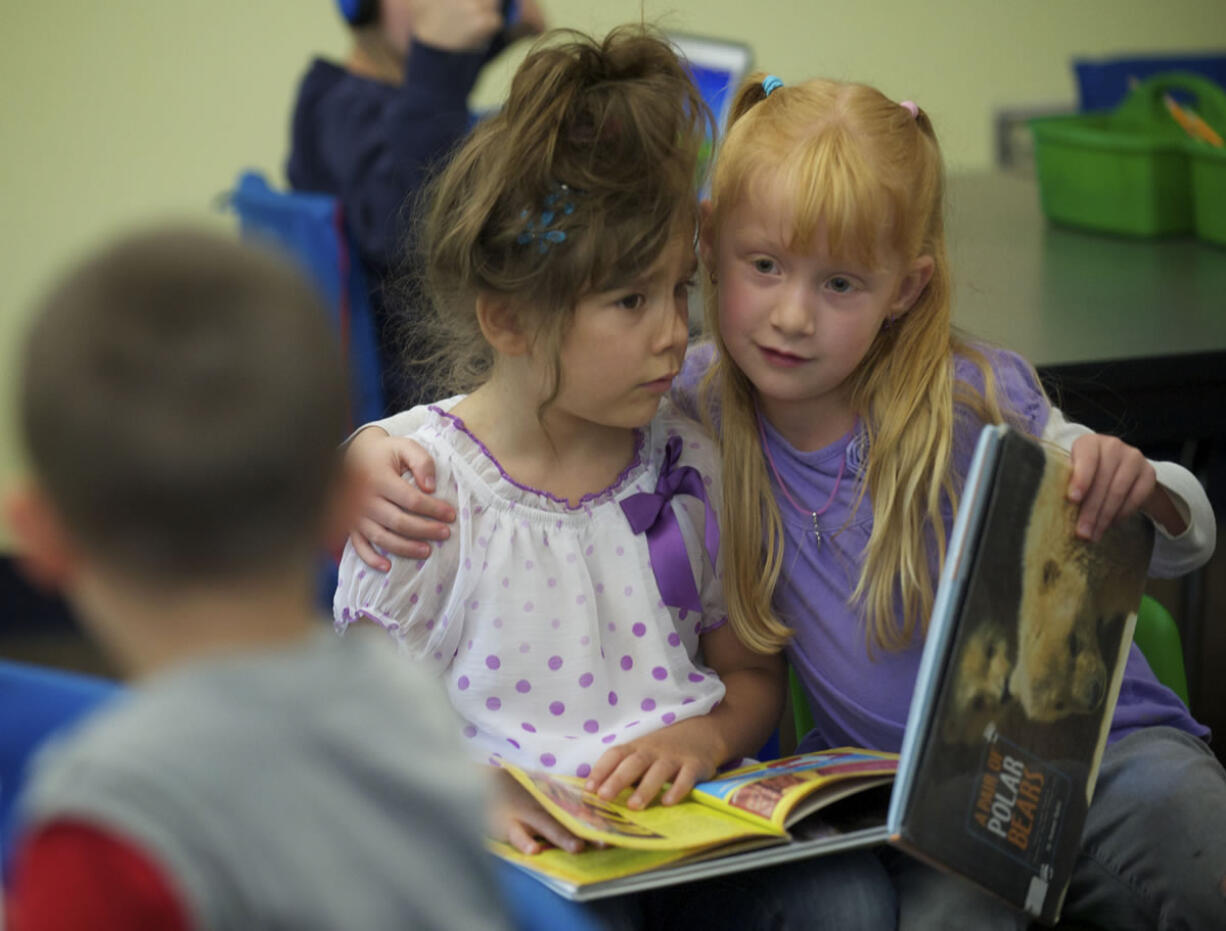 Kindergartner Taima Blackwood, right, gives classmate Maddy Corrington a hug while reading in Wayne Mason's class last month at Endeavour Elementary School.