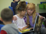 Kindergartner Taima Blackwood, right, gives classmate Maddy Corrington a hug while reading in Wayne Mason's class last month at Endeavour Elementary School.