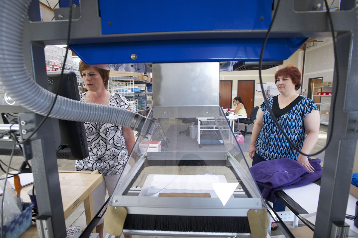 Julie Schoen, left, and Angela DiBetta, owners of Dazzling Design and Apparel, demonstrate a new laser engraving machine Tuesday in Vancouver.