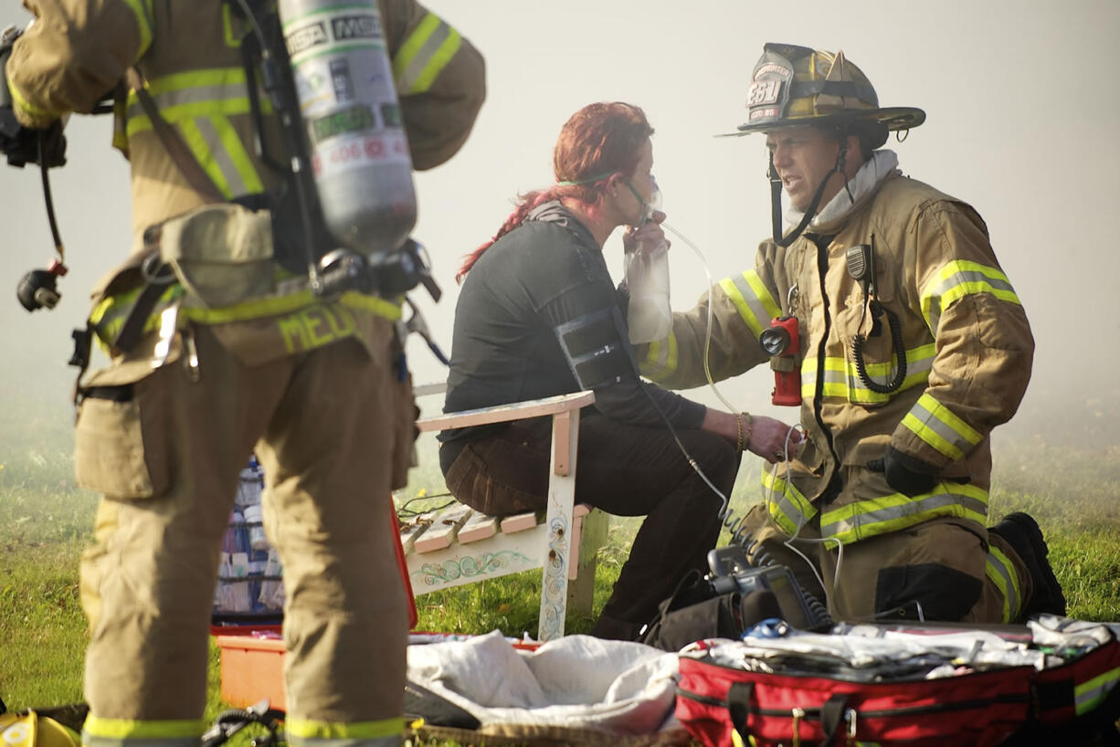 A firefighter with Clark County Fire District 6 assist an occupant of a duplex which caught fire in the Fruit Valley neighborhood Tuesday in Vancouver.