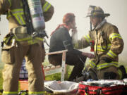 A firefighter with Clark County Fire District 6 assist an occupant of a duplex which caught fire in the Fruit Valley neighborhood Tuesday in Vancouver.