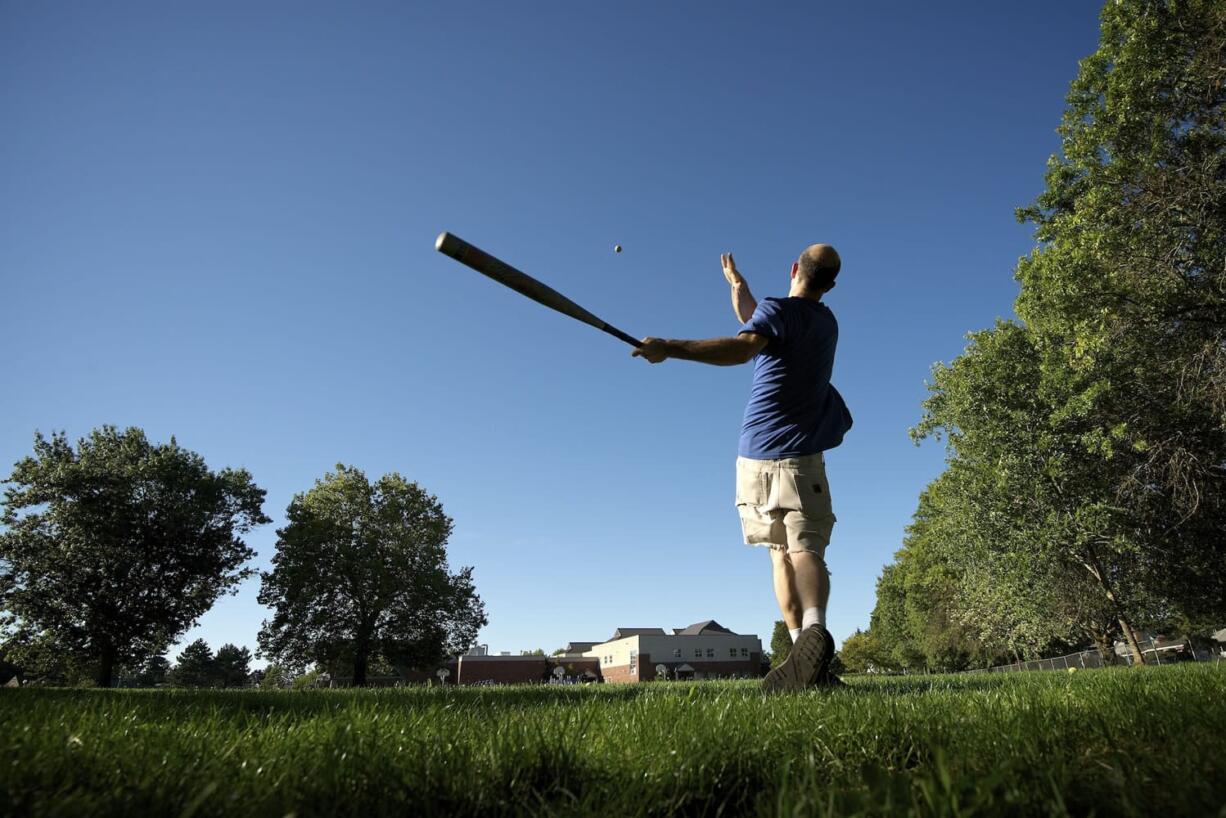 Russell MacArthur hits baseballs to a friend, Robert Straub, at Lincoln Elementary School on Monday in Vancouver.