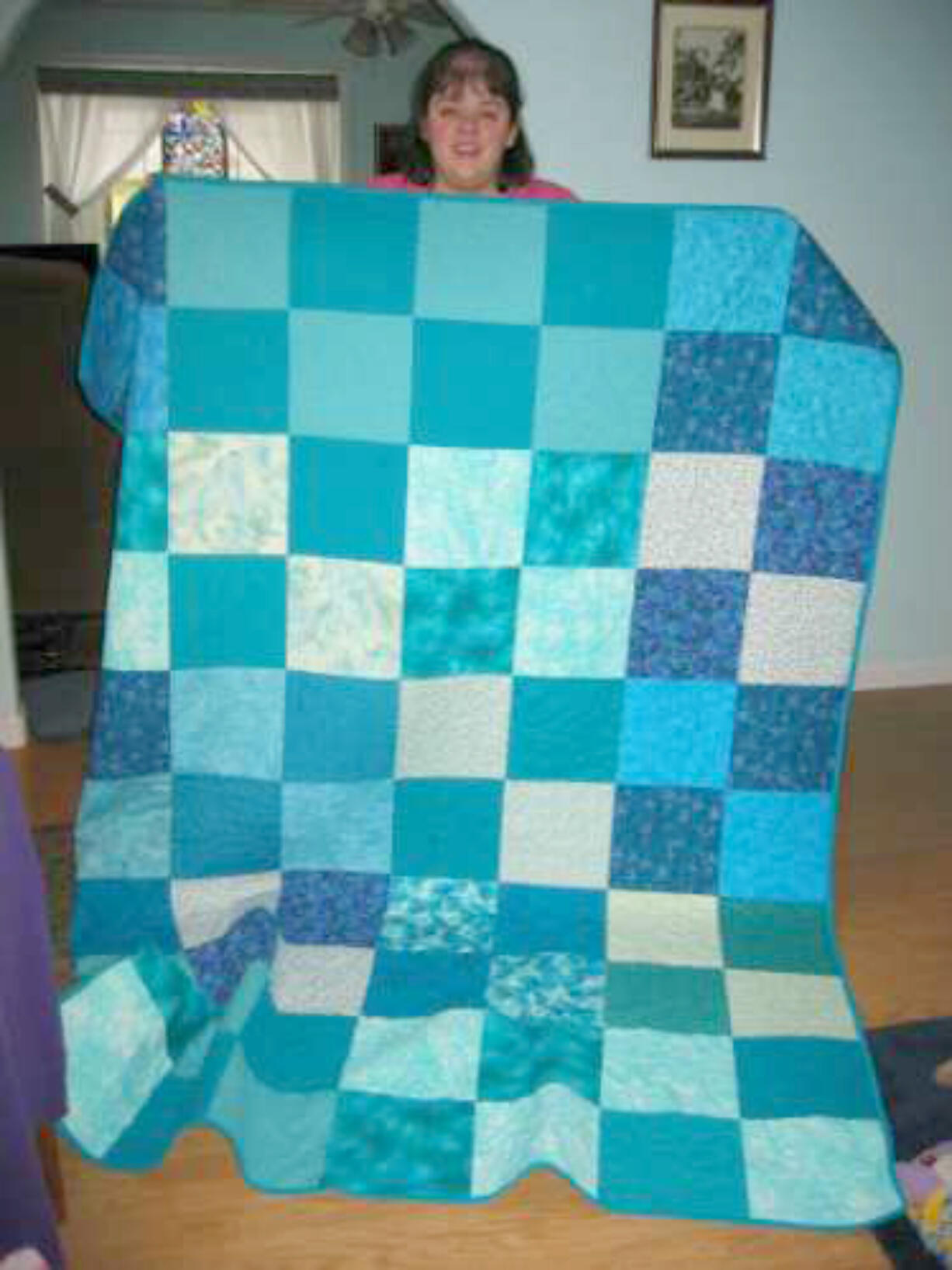 Burnt Bridge Creek: Jeanne LaViollette displays one of the quilts made by the Caritas Quilts.