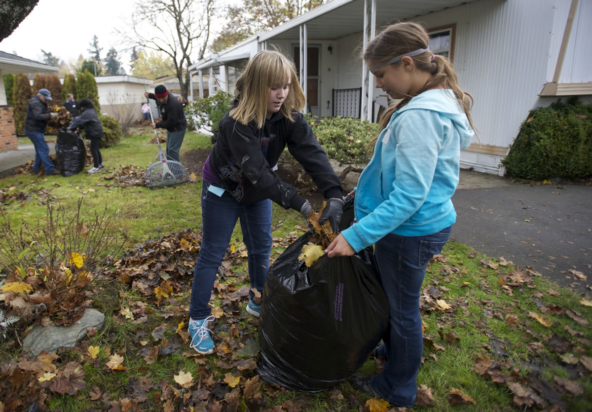 Cornerstone Christian School sixth-graders Samantha Longchamp, left, 11, and Tiffany Mason, 12,  help clear fallen leaves people who need a hand as part of the community service hours required by their school.