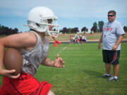 Angel Bonilla, 16, runs past Fort Vancouver's new head coach Todd Quinsey during the Trappers' first practice Wednesday.