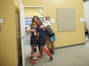 Fourth-grade teacher Kellie Morgan hugs sisters Rylee Griffith, right, 13, and Reagan Griffith, 10, during an open house at the temporary home of Crestline Elementary School. Morgan was a past teacher of Rylee's and Reagan will be a fifth-grader at Crestline this fall. The girls' mother, Janelle Griffith,  a staff assistant at the school, peeks inside the classroom. &quot;We're relieved to be under one roof again,&quot; Morgan said.