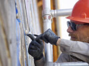 Cary Porter, a maintenance worker at Fort Vancouver National Historic Site, uses a spoon as a tool for smoothing sealant Friday as part of a re-chinking project at the  two-story fur store.