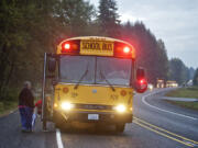 Sharon Norton watches her grandson, 6, board a Woodland School District bus driven by Jolleen Washburn on Friday as traffic stops on Lewis River Road.