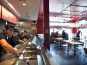 Vincent Mendez, left, and his colleagues get ready to serve the lunch crowd Tuesday at Chipotle Mexican Grill in east Vancouver.