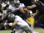 Washington's Chris Polk barely holds on to the football as he runs against the Oregon defense in the first half Saturday.