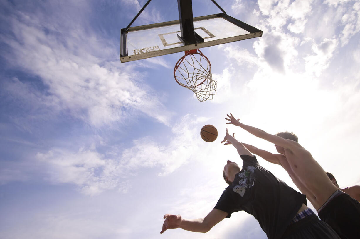 Alex Elliott, 15, left, and Riley Flores, 18, leap for a basketball in a pickup game on a warm afternoon at Washington State University Vancouver on Monday.