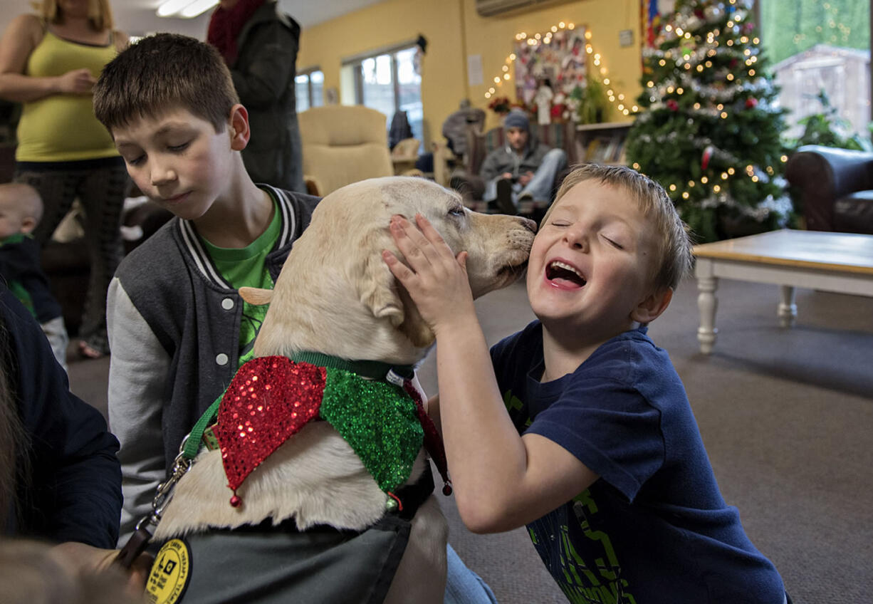 David Anderson, 11, left, pets Limon, a 4-year-old yellow Lab, as his brother, Joey, 6, gets a Christmas kiss on Christmas Eve at the Share Homestead homeless shelter in Hazel Dell.