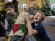 David Anderson, 11, left, pets Limon, a 4-year-old yellow Lab, as his brother, Joey, 6, gets a Christmas kiss on Christmas Eve at the Share Homestead homeless shelter in Hazel Dell.