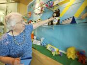 Rosalee Johnson adjusts her display of Olympic mascot plushies at Three Creeks Community Library.