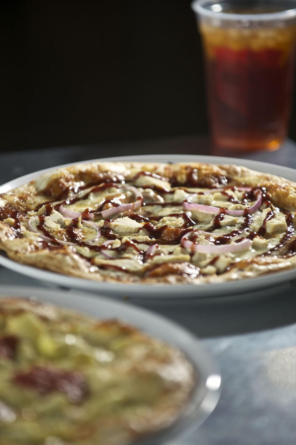 A Lucy Sunshine pizza, foreground, and a Caspian pizza and a caramelized pear iced tea at MOD Pizza.